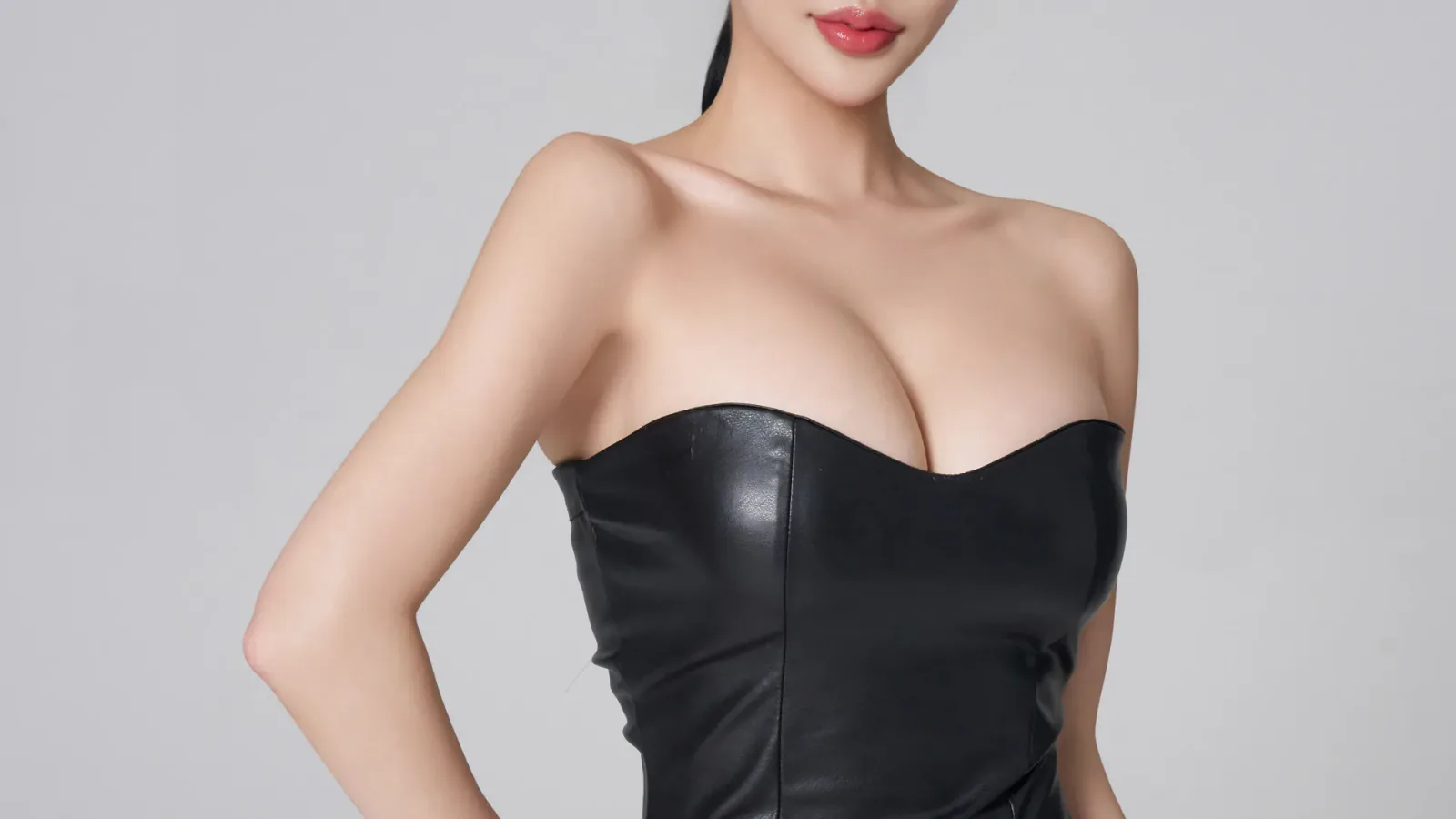 Model in a black strapless top against a grey background