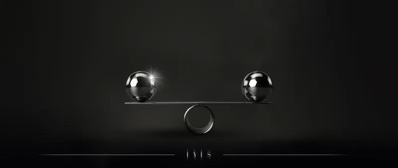 Two metal spheres balanced on a bar against a dark background